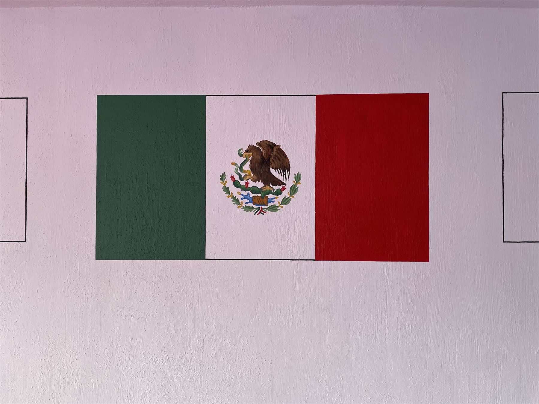 Bandera de México pintada a mano sobre un muro.