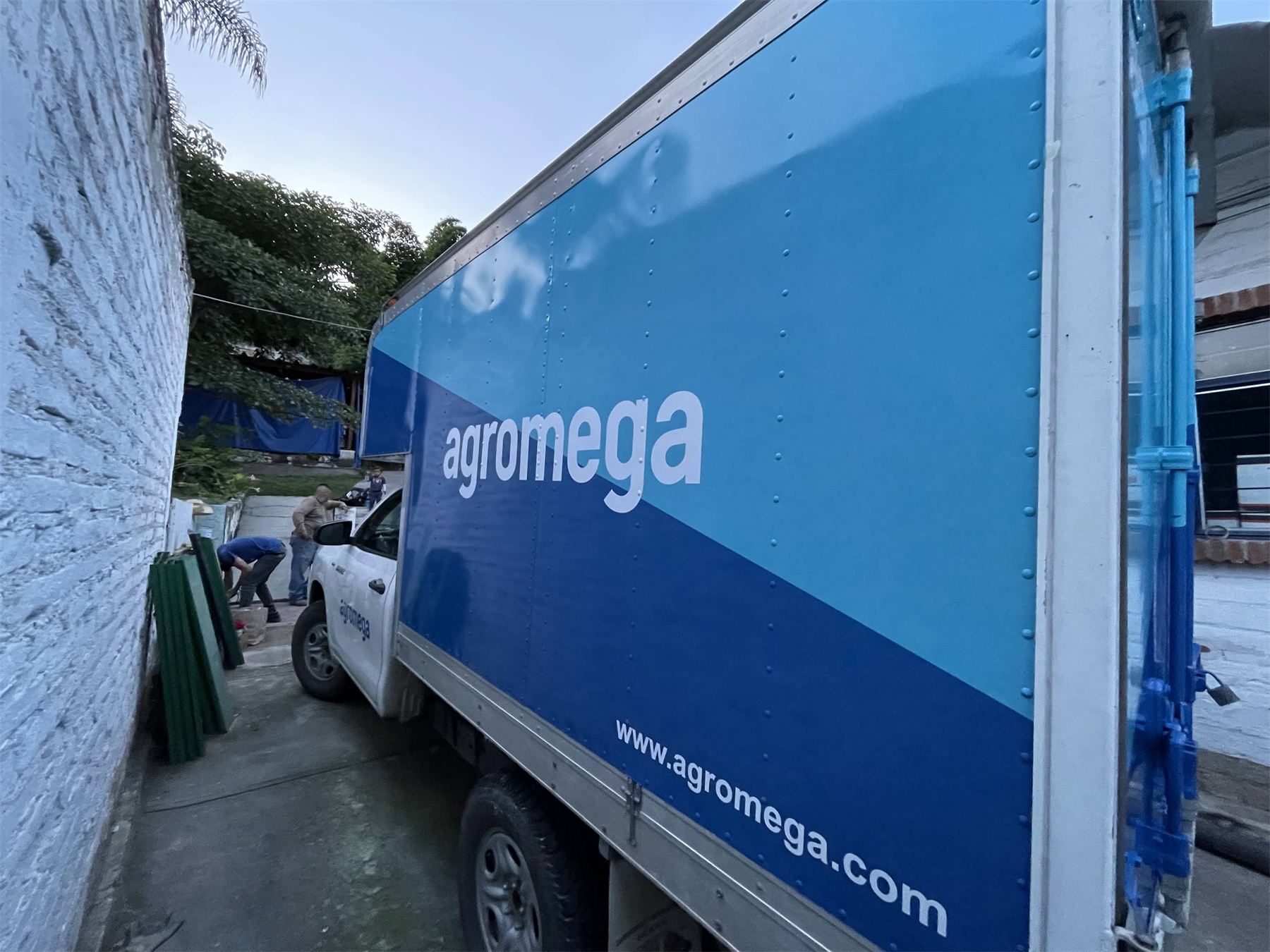 Camión de caja seca rotulado en azul con la marca Agromega.