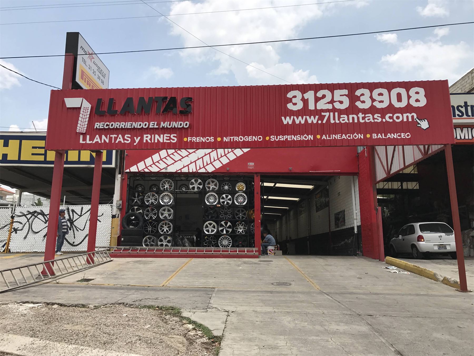 Fachada roja de 7 Llantas con letrero, teléfono y servicios.
