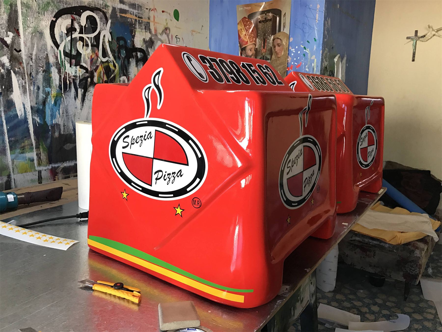 Hornos de pizzería rojos rotulados con el logotipo del negocio.
