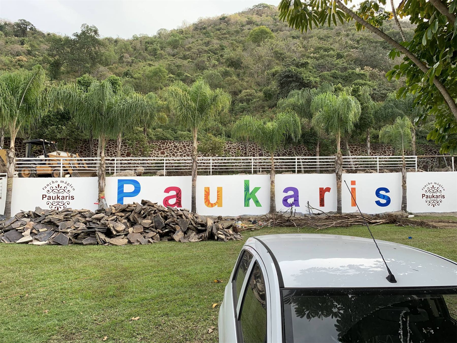 Letras de colores con el nombre Paukaris sobre una barda blanca.