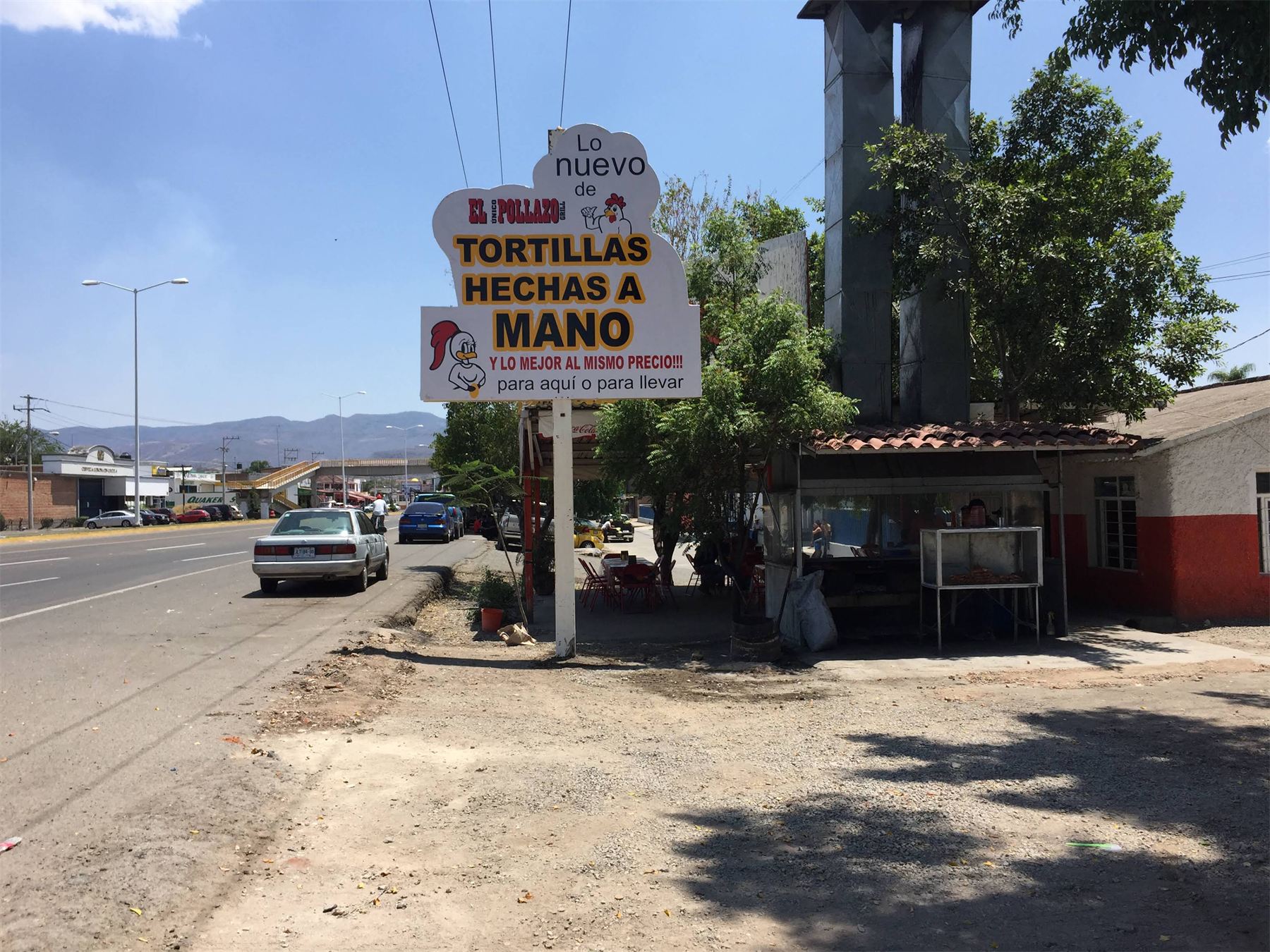 Letrero elevado junto a carretera anunciando tortillas hechas a mano.
