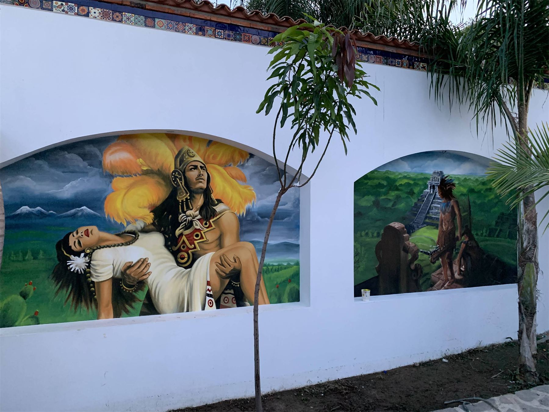 Mural de escenas tradicionales pintado a mano en una barda exterior.