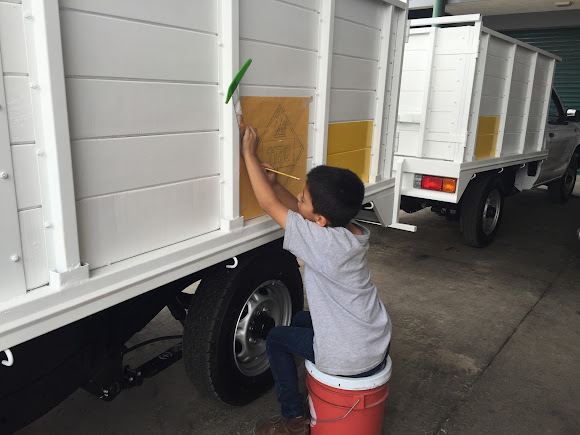 Rotulista trazando a pincel sobre la caja de un camión.