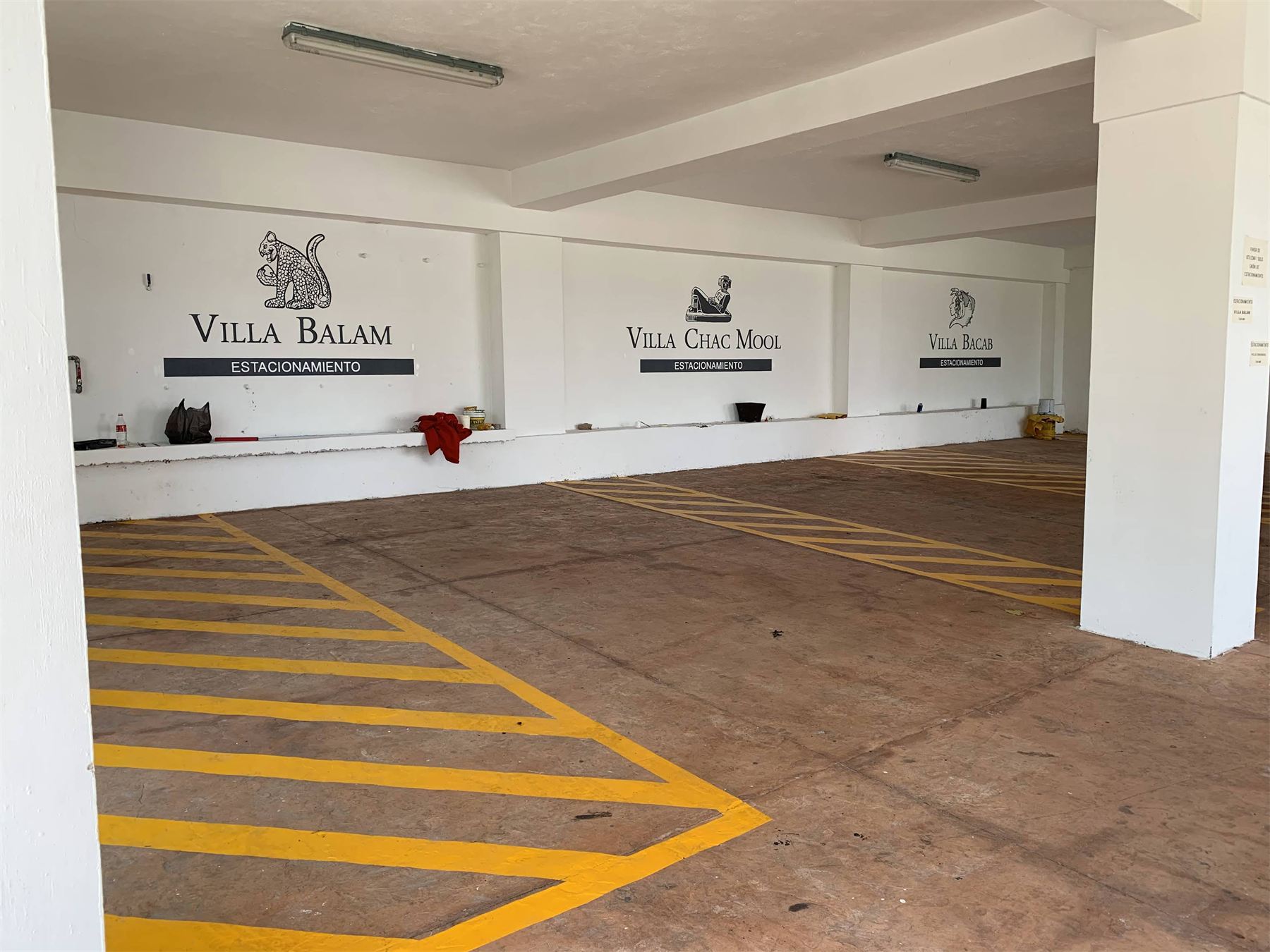 Estacionamiento con líneas amarillas y letras de Villa Balam en muro.